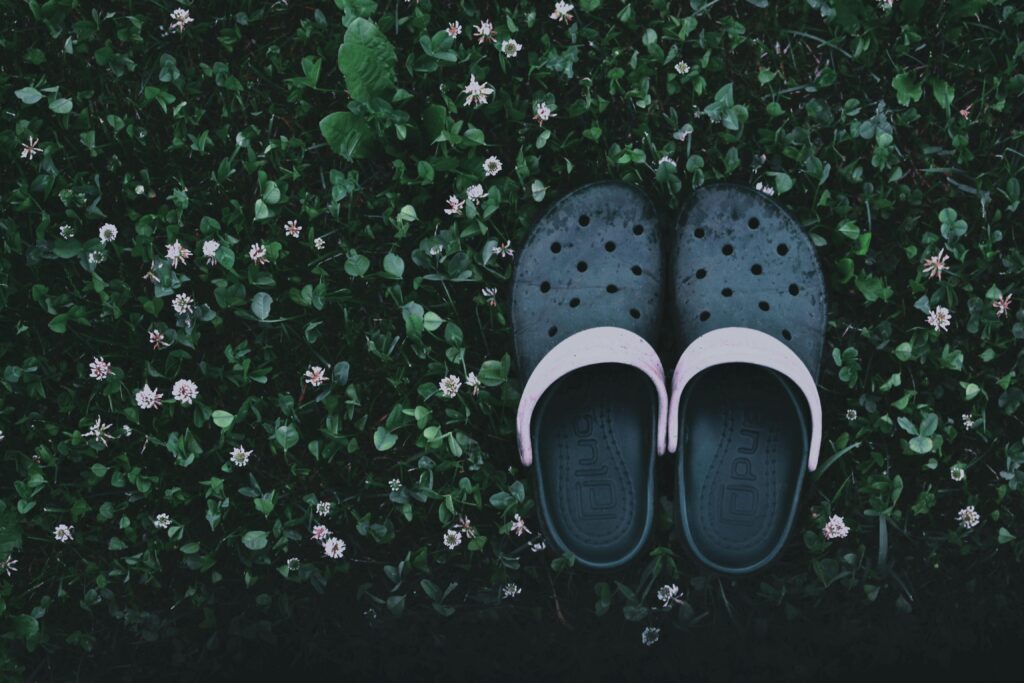 Overhead shot of casual clogs on a lush grass bed with small flowers.